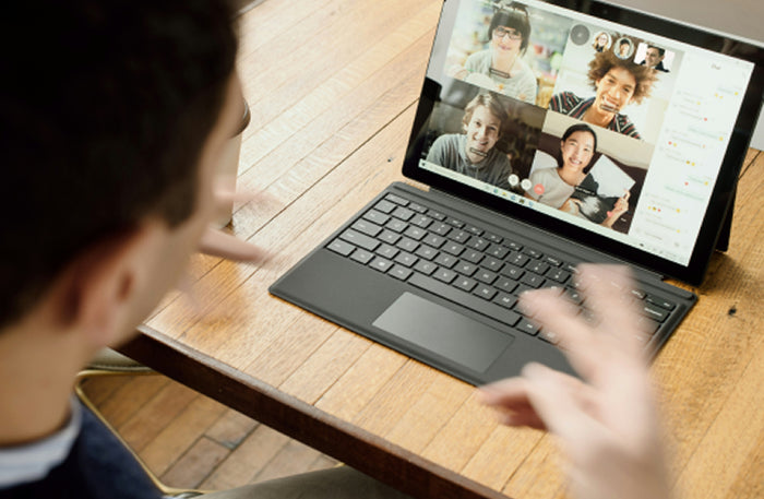 Person using a laptop for business on a video conference call while sitting at a table