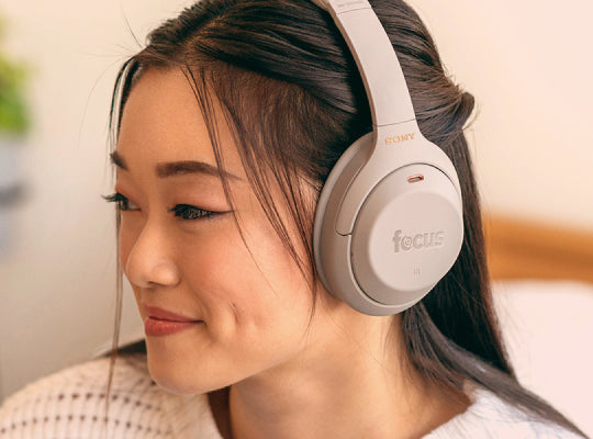 Woman wearing Sony headphones with 'focus' text, displaying customized branding capabilities at Focus Camera B2B & B2G